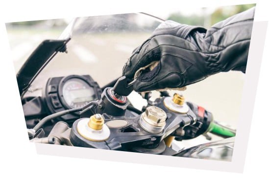 gloved hand turning key in motorcycle ignition